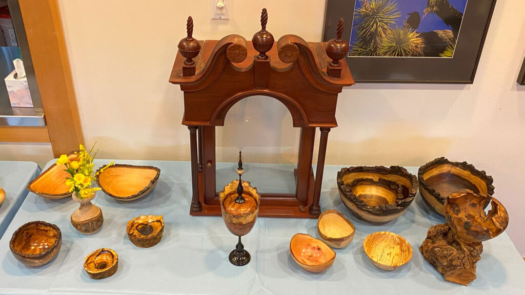 WBW President's Challenge. A table with woodturned projects that have a natural edge -- a tree bark still attached: bowls and vases.