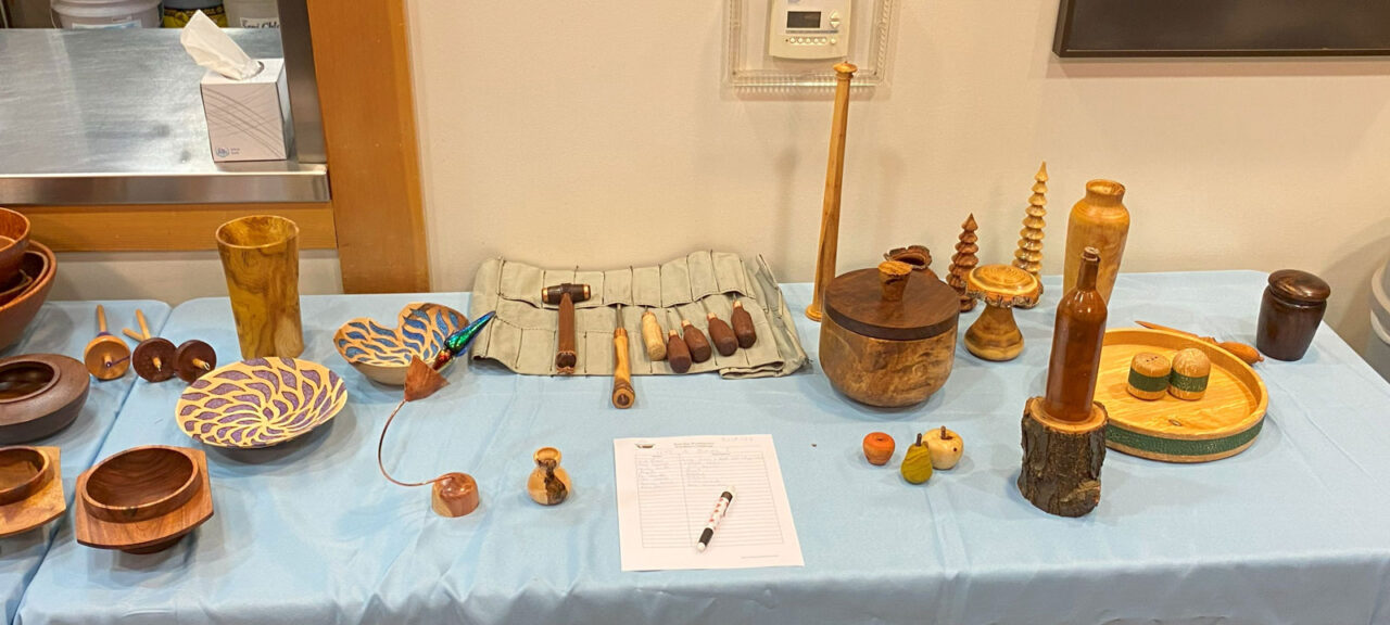 WBW President's Challenge: Not a Bowl. A dozen of woodturning projects are shown on the table. Shared as part of Woodturners Newsletter.