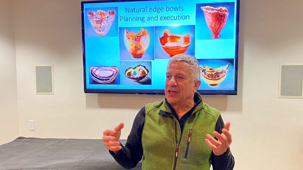 Robert Bley explains how to turn a bowl with live edge and bark inclusions. A slide with seven intricate bowls in the background.