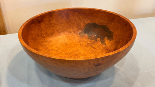A woodturned bowl with an inlay in the shape of a bear.