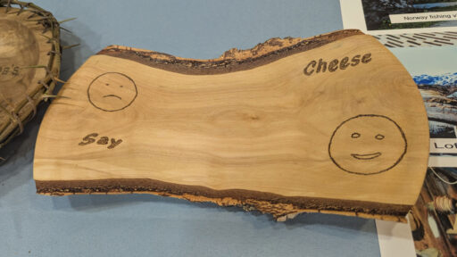 A small wooden slab with the "Say Cheese" woodburning. Sad and happy faces are also woodburned.
