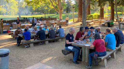 A group of people eating and socializing during a woodturning picnic.