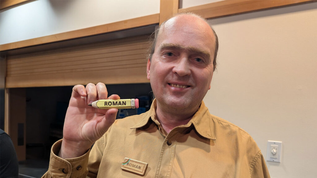 Roman Chernikov whittled his pencil-shaped name badge from a piece of basswood. Visit Roman's website https://readntry.com for more of his woodcarving projects.