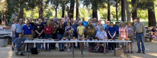 A group of people with a table full of woodturning projects. The photo of WBW and SVW members was taken for the woodturners newsletter.