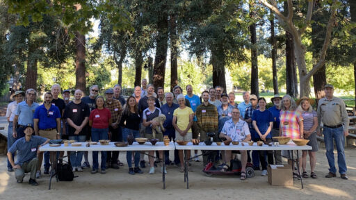 A group of people with a table full of woodturning projects. The photo of WBW and SVW members was taken for the woodturners newsletter.
