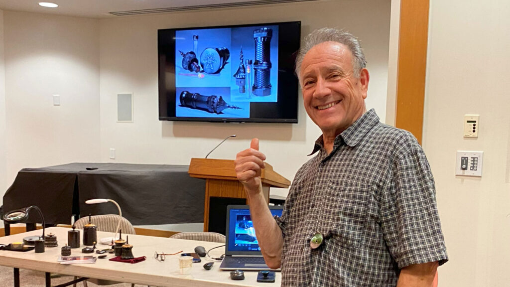Jon Sauer points to a slide of his presentation about ornamental turning and his woodturning projects.