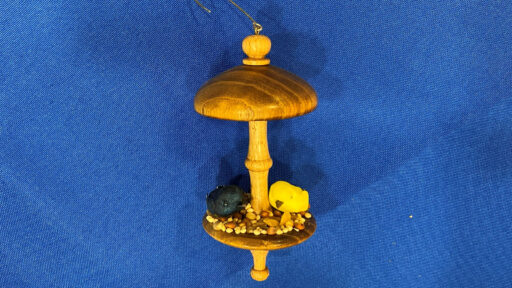 A turned bird feeder with seeds and tiny birds.