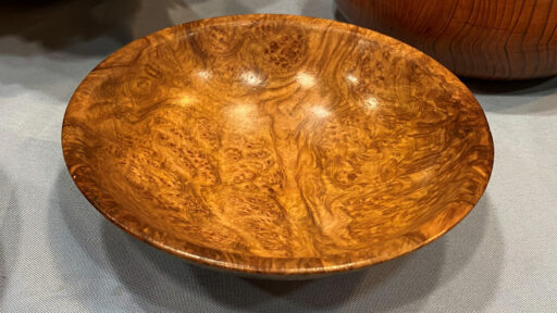 A large platter turned from burl with wild wooden grain.