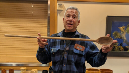 Bob Bley is showing a huge spoon that he turned on a lathe.