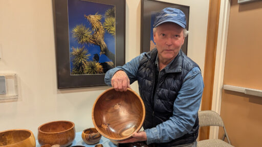 Dennis Lillis is showing a large calabash bowl with butterfly decorations inlaid inside.