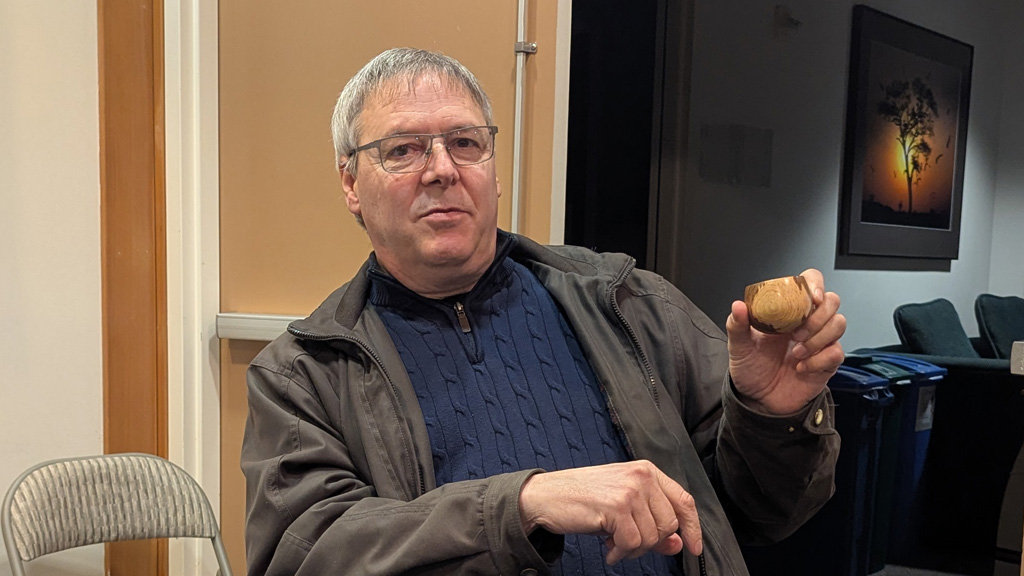 Kevin is showing a tiny calabash bow that he turned on a lathe.