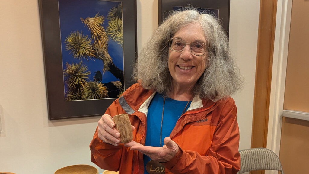 Laura is showing a tall, tiny calabash bowl that was recently turned from acacia wood.
