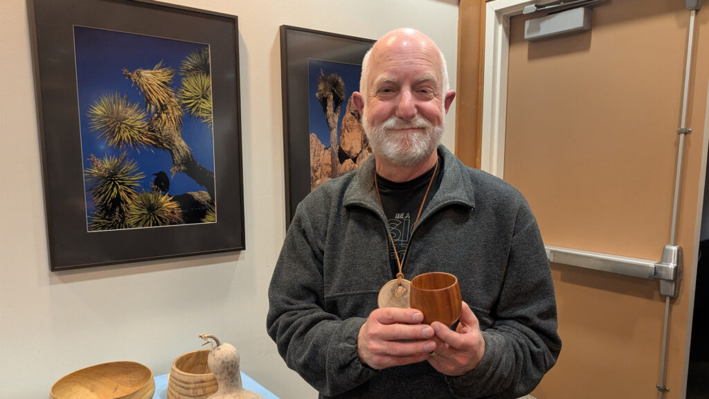 Vic Mitnick is showing a tall calabash bowl that he recently turned on a lathe.