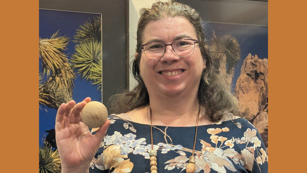 Angela shows a wooden sphere that she turned on a lathe