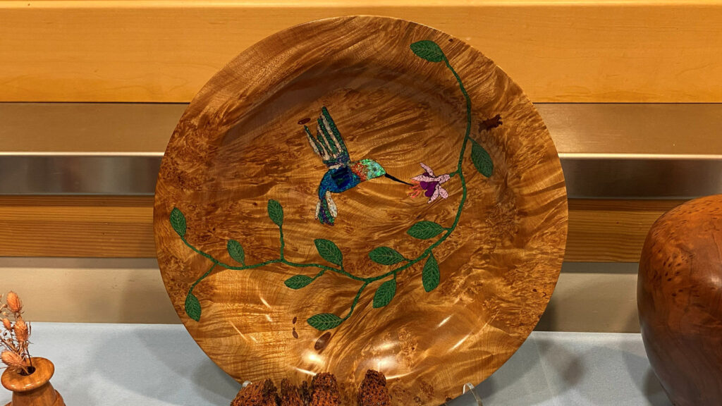 Gorgeous maple burl platter with a hummingbird and flower design inlaid with stone, turned by Bob Bley.