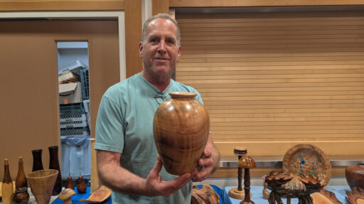 Dan is holding a large hollow form that he turned on a lathe.