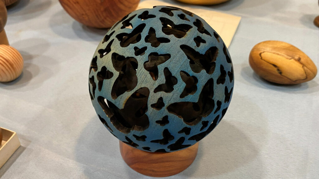 A hollow sphere with a butterfly design pierced and burned into it.