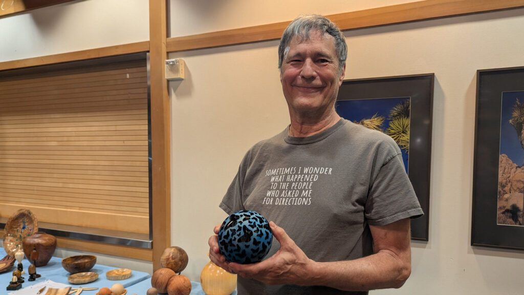 David is holding a hollow sphere with a butterfly design pierced and burned into it that he turned on a lathe.