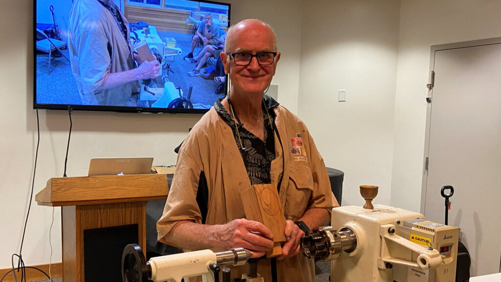 Edgar is holding a Redwood blank for turning an egg on a lathe.