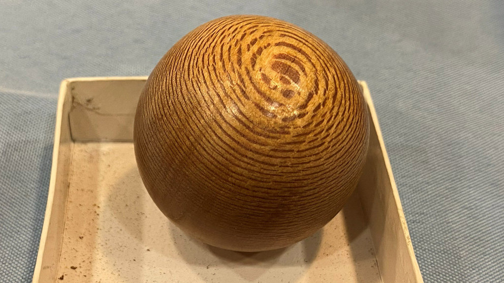 A wooden sphere turned on a lathe.