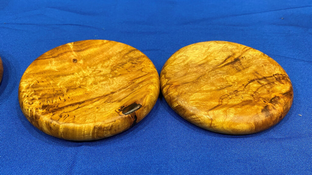 Two coasters turned from light-colored wood with beautiful grain by Jon Bishop on a lathe.