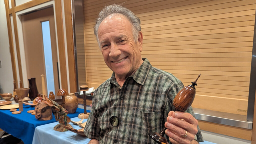 Jon is holding an egg-shaped box that he turned on an ornamental lathe.