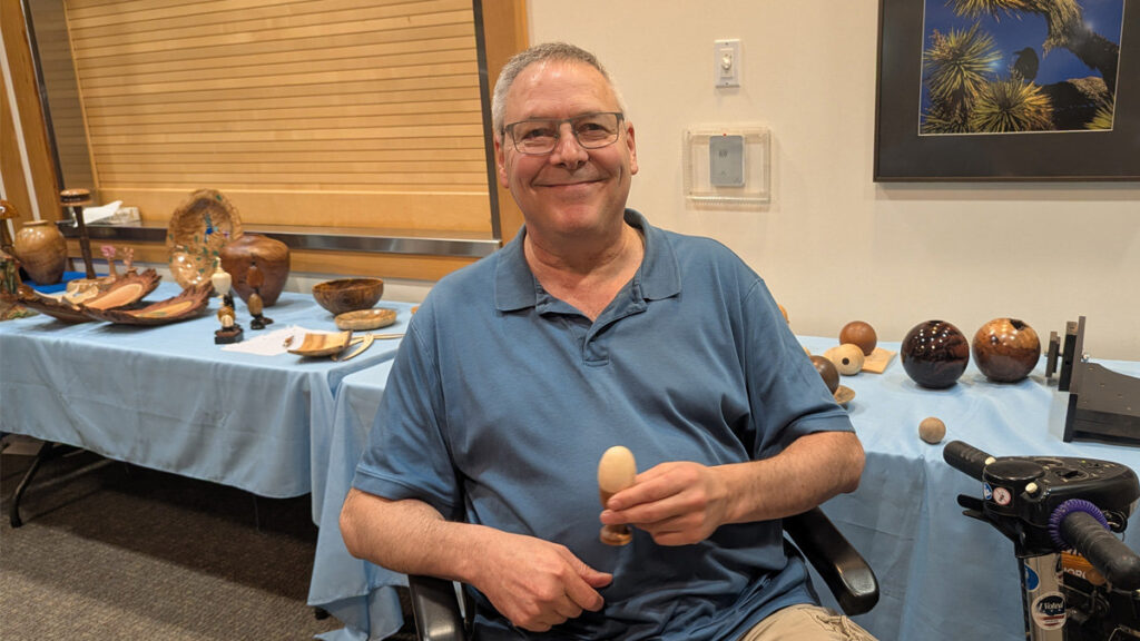 Kevin is holding an egg in an egg stand that he turned on a lathe.