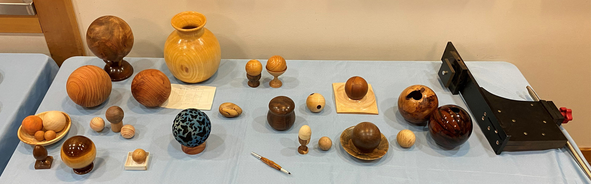 Dozens of turned wooden spheres and a few eggs. The image includes a jig for turning spheres.
