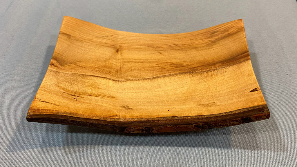 Square bowl turned on a lathe from light-colored wood.