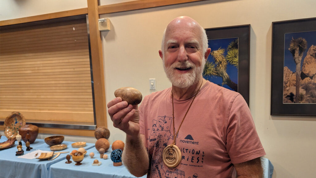 Vic is holding a wooden egg that he turned on a lathe.