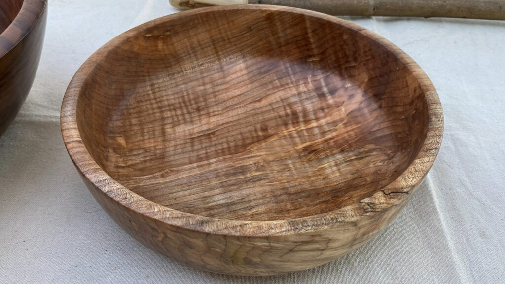 A turned wooden bowl with rich, reddish-brown figured grain, created by Jerry Galli.