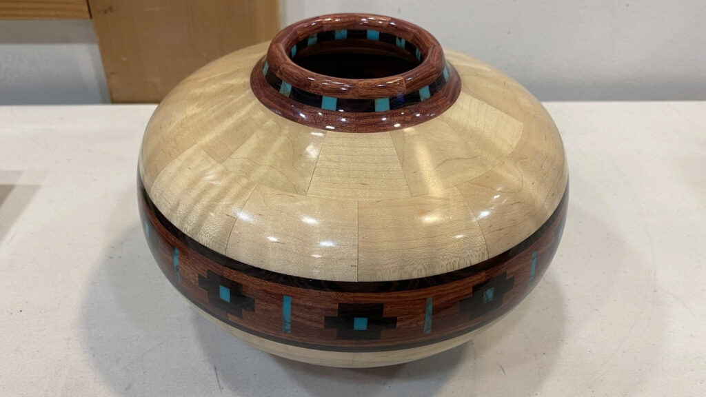 Hand-turned segmented vessel by Gordon Peterson featuring soapstone and turquoise inlays, displayed on a table at a West Bay Woodturners meeting in Los Altos, California.